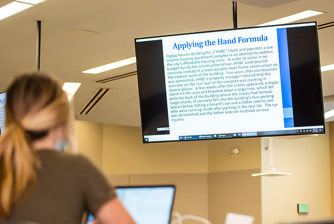 Student on computer classroom looking at large monitors