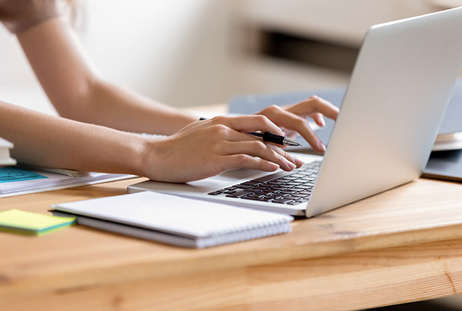 person typing with laptop and notebook