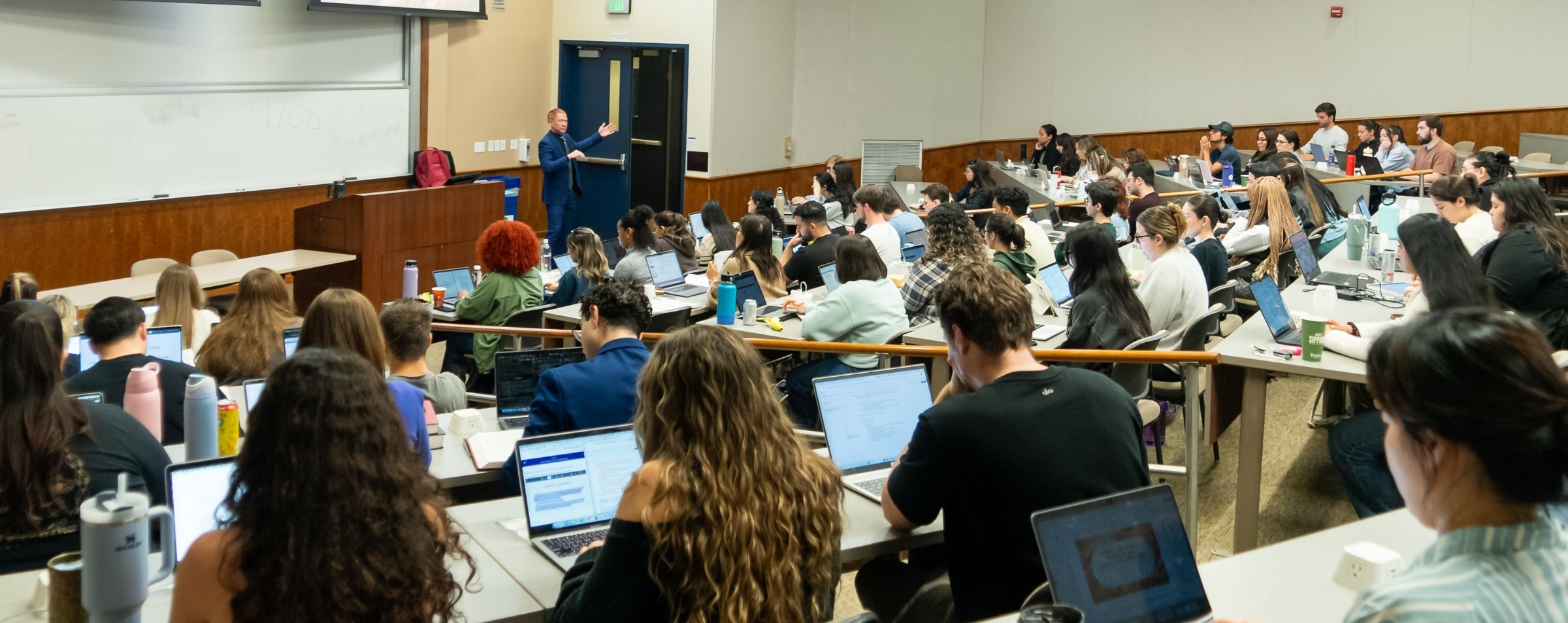 Students taking notes on laptop during a class lecture