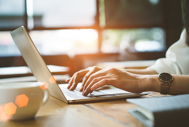 woman typing on a computer with coffee