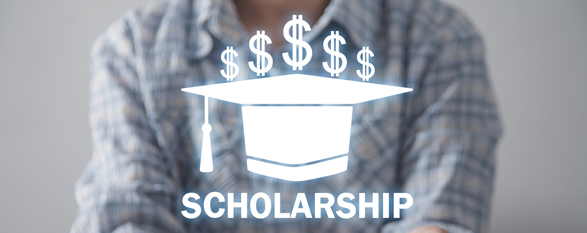 person holding graduation cap with the word scholarships and money signs