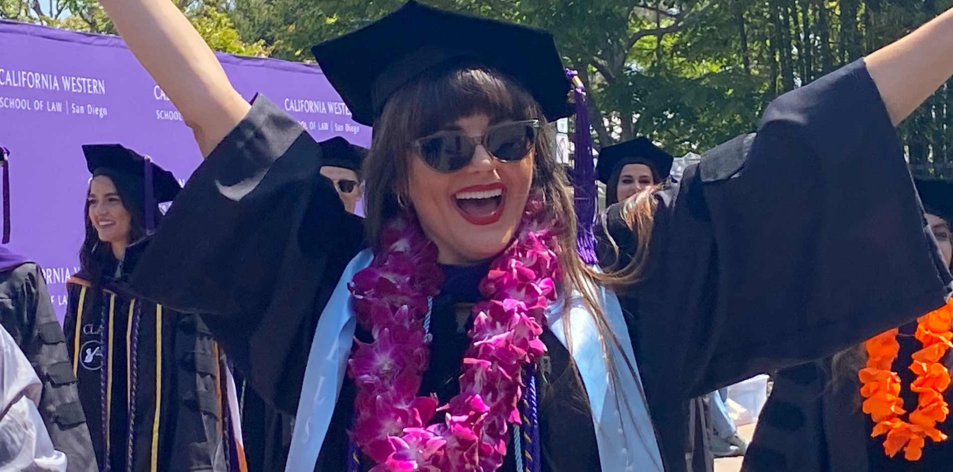 Female student raising hand in celebration at graduation