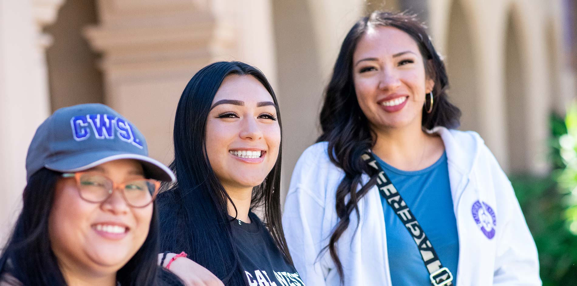 Three females students laughing while hanging out in Balboa Park