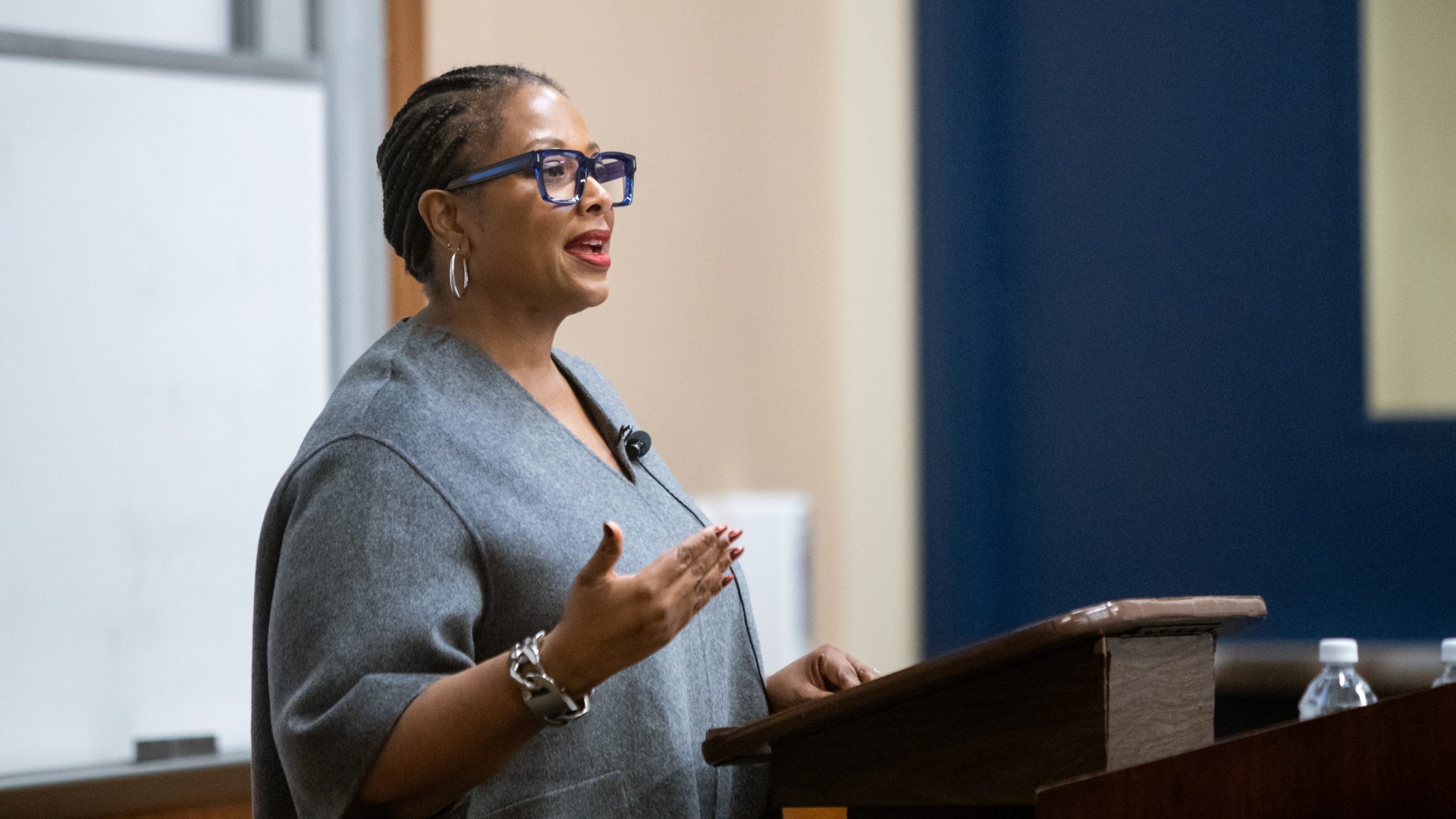 Deborah Archer stands at the lectern in a gray dress, black glasses, and silver jewelry.