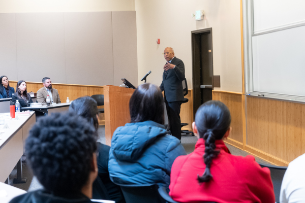 Randall Kennedy stands at the lectern giving a lecture with the backs of an audience in the foreground.