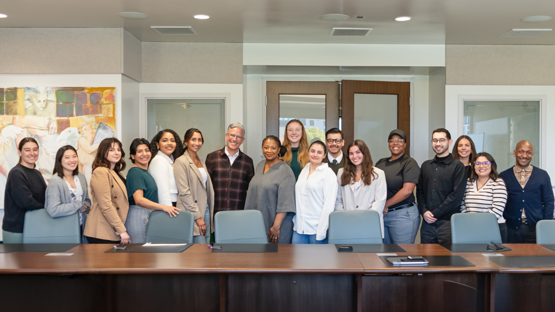 A large group of students gather around Deborah Archer for a group photo in the conference room.