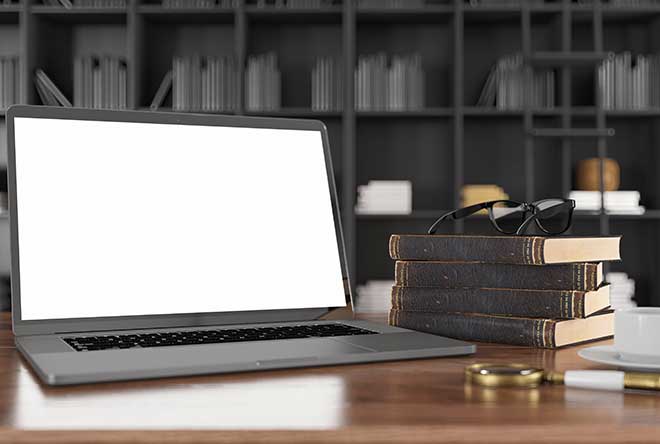 Blank laptop on desk with books