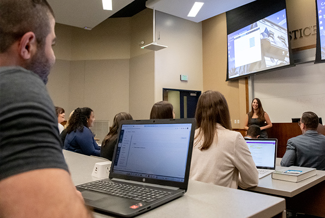 Student with laptop taking notes during lecture