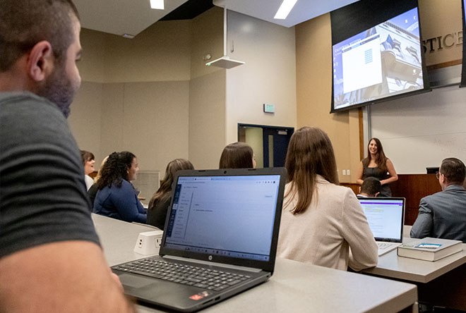 Student taking notes on a laptop during a lecture