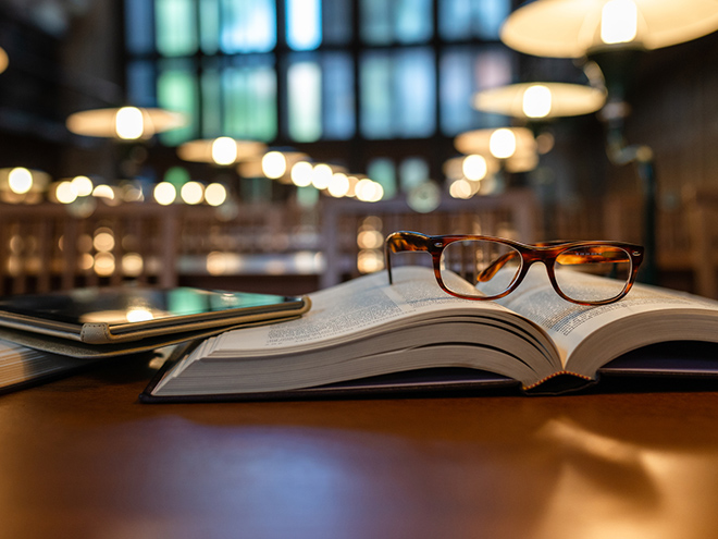 Glasses on top of book with Ipad in library