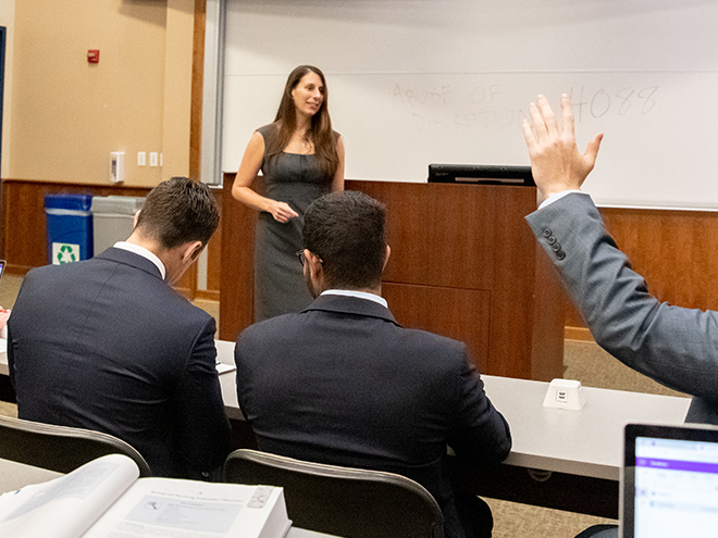 Student raising their hand during a class with Professor Erin Sheley 
