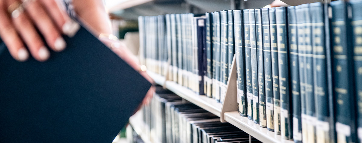 Student pulling a book off the shelf